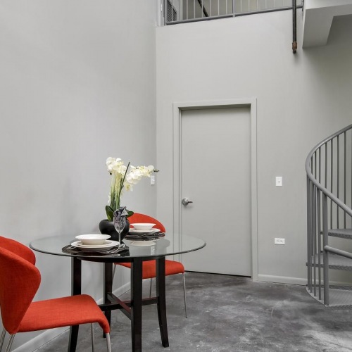 a table with a chair and a staircase in the background