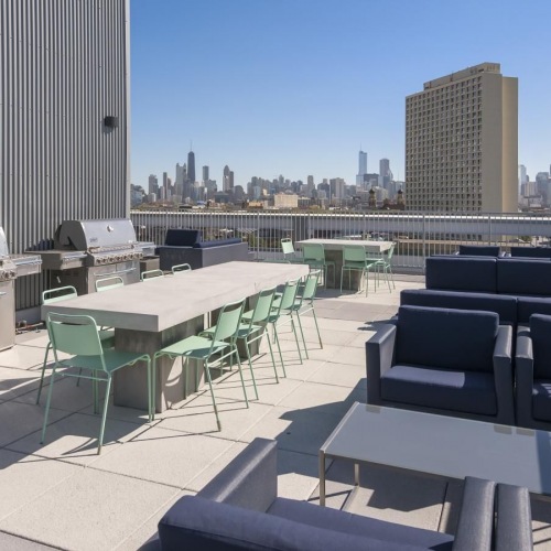 a patio with tables and chairs and a body of water in the background